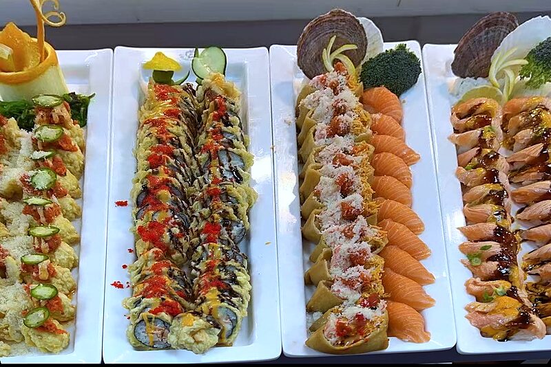 Four platters of sushi rolls and salmon nigiri